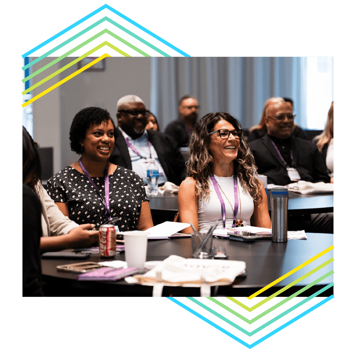 2 smiling conference attendees at a round table with open notebooks