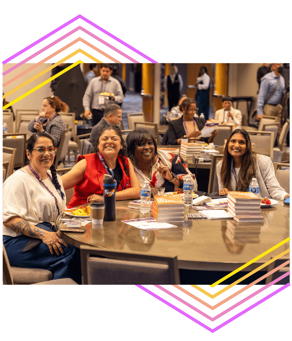 4 conference attendees at a round table with stacks of books