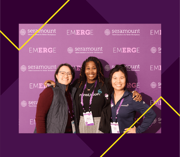 3 people standing in front of a Seramount EmERGe branded purple fabric backdrop